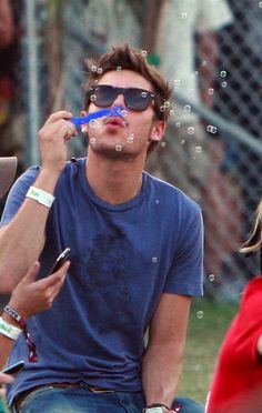 a man with sunglasses blowing bubbles on his face