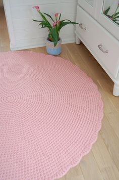 a pink rug in the corner of a room with a potted plant next to it