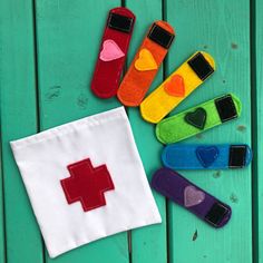 several colorful felt pieces with hearts and crosses on them sitting next to a white cloth bag