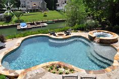 an outdoor swimming pool surrounded by stone steps and patio furniture, with a hot tub in the middle