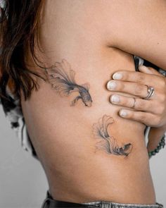 a woman's back with tattoos on her body and one hand holding the other