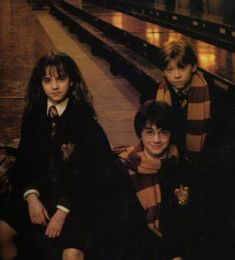 three young harry potters sitting on the floor in front of a building with their arms around each other