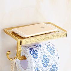 a gold toilet paper holder with a cell phone on it