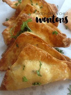 four pieces of food sitting on top of a white paper wrapper with green chives