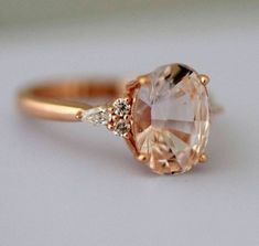 a close up of a ring with an oval shaped stone and two small diamonds on the side