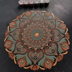 an intricately designed rug on the floor in front of some containers with paint and pencils