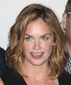 a close up of a person wearing glasses and a black top with a smile on her face