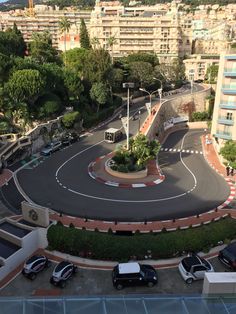 an aerial view of a city street with cars parked on the road and buildings in the background