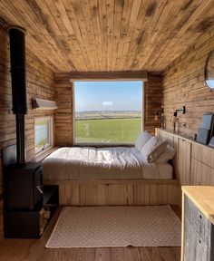 a bedroom with wood paneling and a bed in front of a window that looks out onto a field