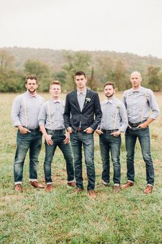 a group of men standing next to each other on top of a grass covered field