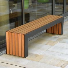 a wooden bench sitting in front of a glass window next to a tiled floor and wall