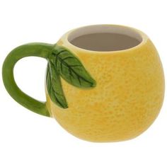 a yellow ceramic mug with a green leaf on the handle and inside, sitting in front of a white background