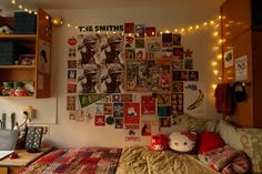 a bedroom with lots of pictures on the wall and lights strung from the ceiling over the bed