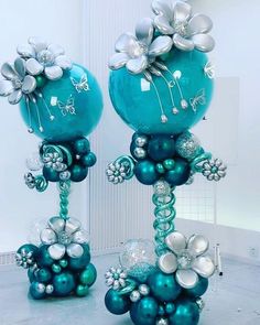 two blue balloons with silver and white flowers on them are standing in the middle of a room