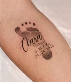 a close up of a person's foot with a hand and footprints tattoo on it