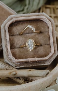 an engagement ring sits in a box on top of some driftwood