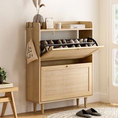 a wooden shelf with shoes on it in front of a white wall and a window