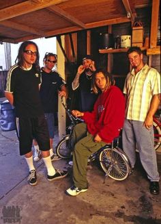 a group of men standing next to each other in front of a garage with bicycles