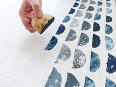 a person is using a sponge to paint on fabric