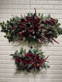 two wall hangings with flowers and greenery on them against a white brick wall