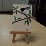 a small easel with a bird painted on it