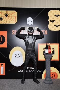 a man dressed as a spiderman standing next to a fire hydrant and halloween decorations