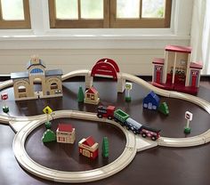 a toy train set is sitting on a table with other wooden toys and buildings around it