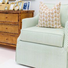 a green and white striped chair sitting next to a dresser