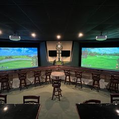 an empty room with tables and chairs in front of two large screens