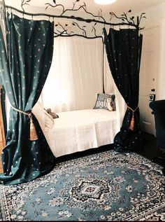 a canopy bed in a bedroom with blue curtains and a rug on the floor next to it