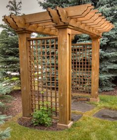 a wooden pergola in the middle of some grass