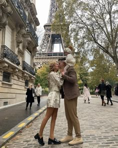 a man and woman kissing in front of the eiffel tower