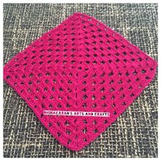 a pink crocheted square sitting on top of a carpet