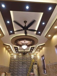 a ceiling fan in the middle of a room with lights on and stairs leading up to it