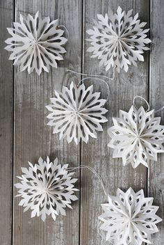 white paper snowflakes hanging from string on wooden surface