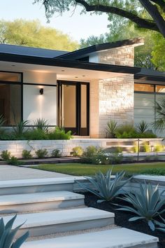 a modern house with steps leading up to the front door and landscaping area around it