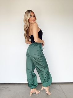 Introducing the Green Light Cargo Pants. Featuring an adjustable tie waistband with cargo pocket details and a jogger fit for ultimate comfort, these pants are perfect for a special night out or a casual day of errands. Elevated with a high-waisted, rich and soft texture, this trendy and versatile piece exudes luxury and sophistication. Perfect for dinner, drinks, lounging, and more. 100% Nylon Hand wash cold. Light Cargo Pants, Dinner Drinks, Shell Suit, Hip Hop Streetwear, Cargo Pocket, Green Light, Soft Texture, Hunter Green, Pocket Detail