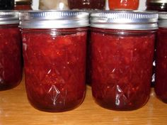 jars filled with red liquid sitting on top of a wooden table