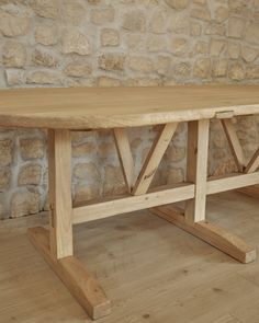 a wooden table sitting on top of a hard wood floor next to a stone wall