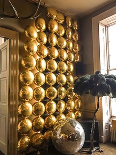 a room filled with lots of shiny gold balls on the wall next to a potted plant