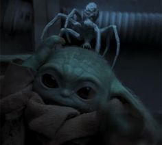 the baby yoda is sitting on top of someone's head with an object in its hand