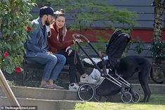 a man and woman sitting on steps with a baby in a stroller next to a dog