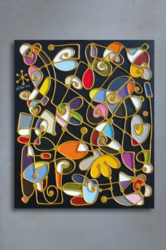 an abstract painting with many different colors and shapes on black paper, hanging on a wall