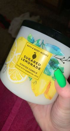 a hand holding a jar of bath and body works sugared lemonade scented candle