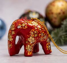 a red elephant figurine sitting on top of a table next to christmas ornaments