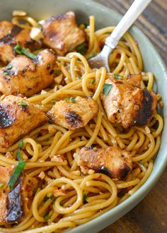 a bowl filled with chicken and noodles on top of a wooden table