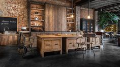 an industrial style kitchen with brick walls and exposed ceilings, wooden cabinets, and bar stools