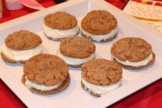 there are six cookies with cream fillings on the white plate and red tablecloth