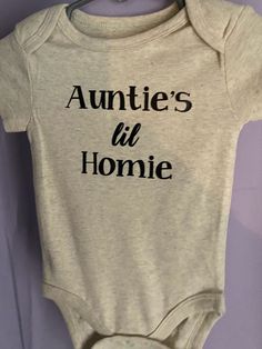 an infant's bodysuit with the words auntie's lil homie printed on it