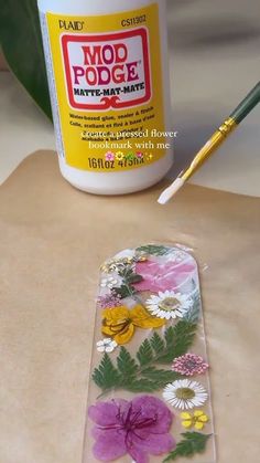 a bottle of glue sitting next to a flower covered piece of paper with flowers on it